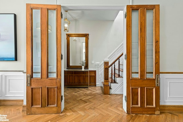 hall with a decorative wall, stairway, and a wainscoted wall