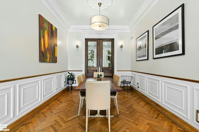 dining room with a decorative wall, ornamental molding, and a wainscoted wall