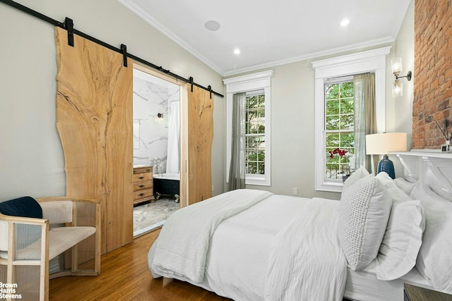 bedroom featuring recessed lighting, a barn door, ornamental molding, and wood finished floors