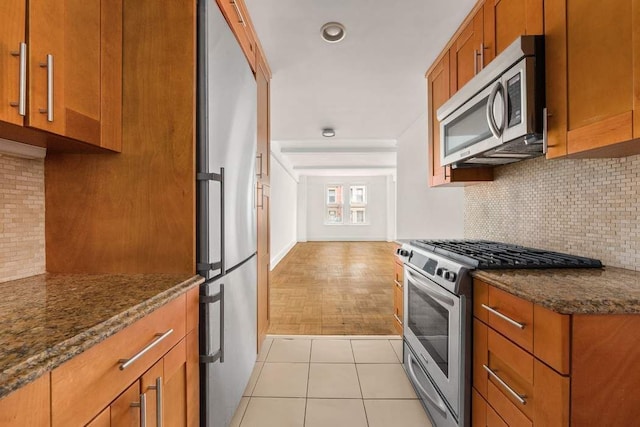 260 W End Ave Unit 3D, New York City, NY 10023 - kitchen featuring stainless steel appliances, backsplash, brown cabinetry, and dark stone countertops