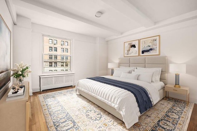 260 W End Ave Unit 3D, New York City, NY 10023 - bedroom featuring radiator heating unit, beam ceiling, wood-type flooring, and baseboards