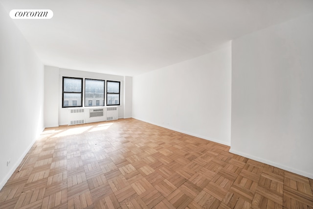spare room with baseboards and radiator