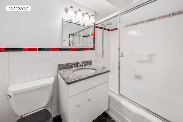 full bathroom featuring tile walls, combined bath / shower with glass door, toilet, and vanity
