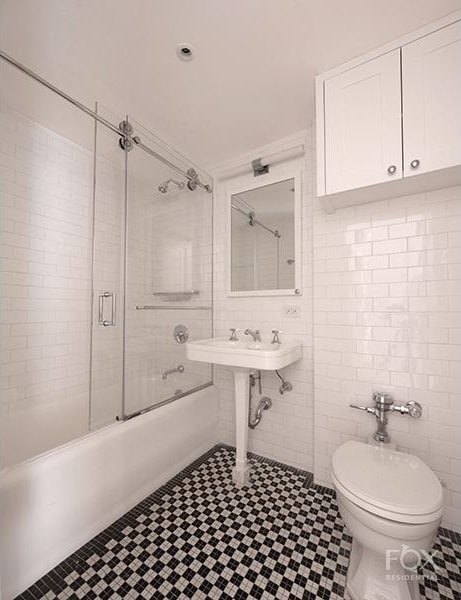 full bathroom featuring tile walls, combined bath / shower with glass door, toilet, and tile patterned floors