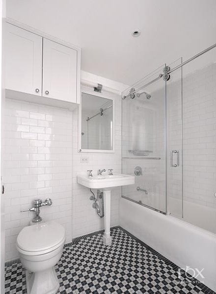 bathroom with tile walls, toilet, enclosed tub / shower combo, tile patterned floors, and a sink