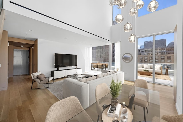 dining space featuring wood finished floors, a chandelier, and a high ceiling