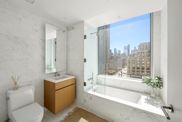 611 W 56th Street Maisonwest, New York City, NY 10019 - full bath with tile walls, a view of skyline, a tub with marble appearance, toilet, and vanity