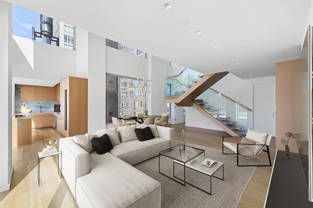 living area with light wood-style flooring, stairs, and healthy amount of natural light