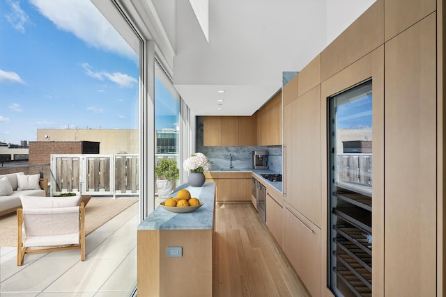 kitchen featuring a sink, open floor plan, light wood-style floors, modern cabinets, and backsplash