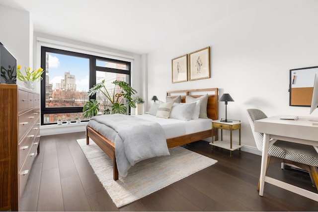 bedroom featuring dark wood-type flooring, a city view, and baseboards