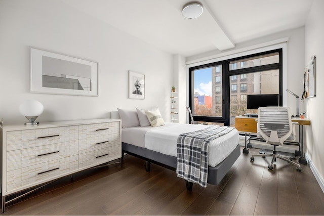 bedroom with dark wood-style floors, an office area, and baseboards