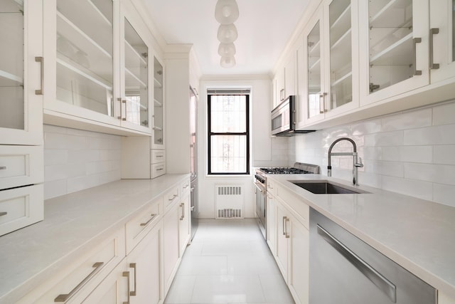 kitchen featuring a sink, appliances with stainless steel finishes, backsplash, glass insert cabinets, and light countertops