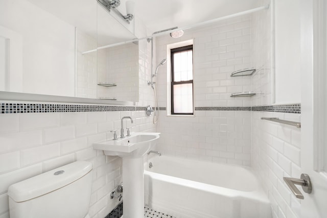 full bath with tile walls, toilet, and washtub / shower combination