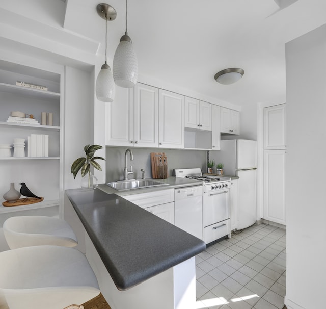 kitchen with a peninsula, a sink, white appliances, and white cabinets