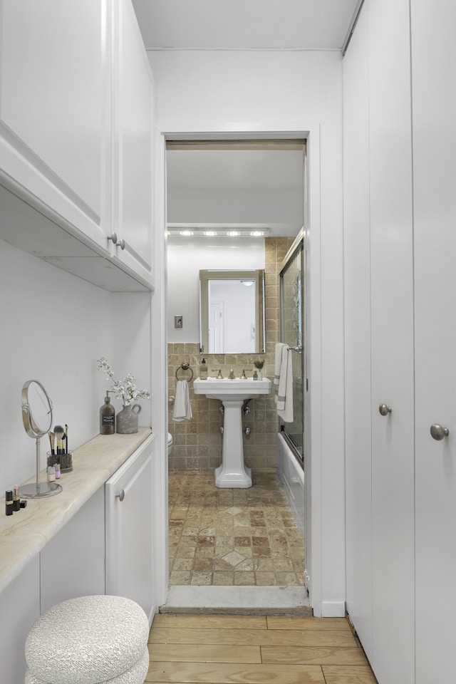bathroom with shower / bath combination with glass door, toilet, and wood finished floors