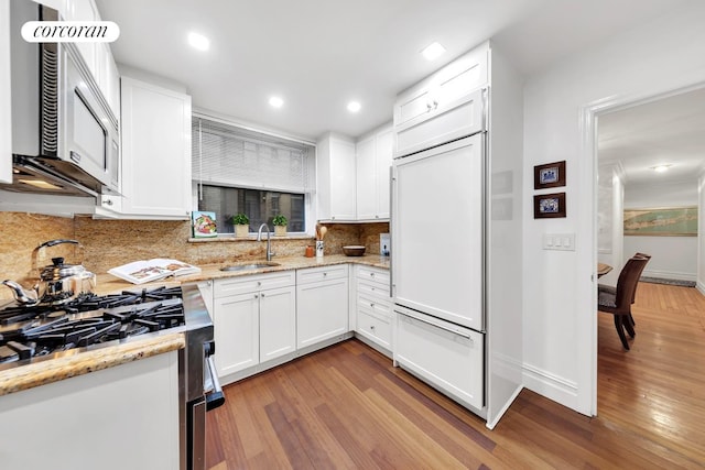 49 E 86th St Unit 3A, New York City, NY 10028 - kitchen featuring paneled built in fridge, light wood-style flooring, a sink, stainless steel gas stove, and recessed lighting