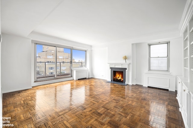 unfurnished living room featuring a lit fireplace and baseboards