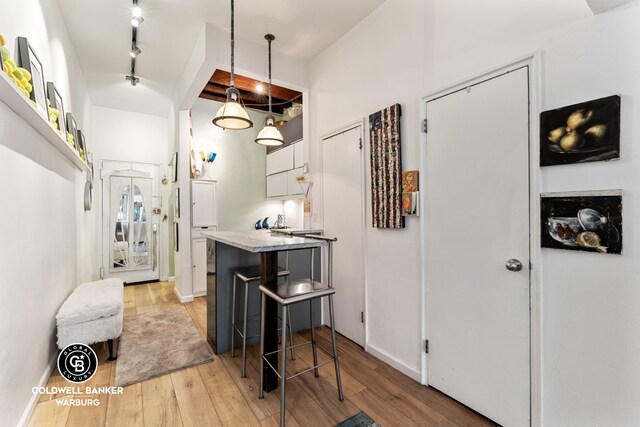240 E 32nd St Unit 1A, New York City, NY 10016 - kitchen with light wood-style floors, track lighting, pendant lighting, a breakfast bar area, and white cabinets