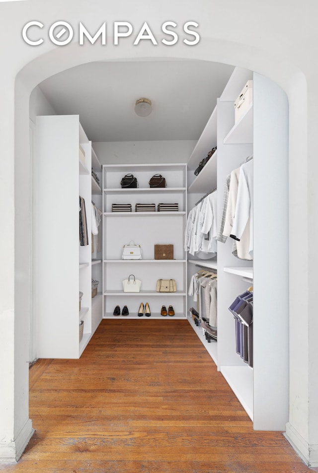 spacious closet featuring wood finished floors and arched walkways