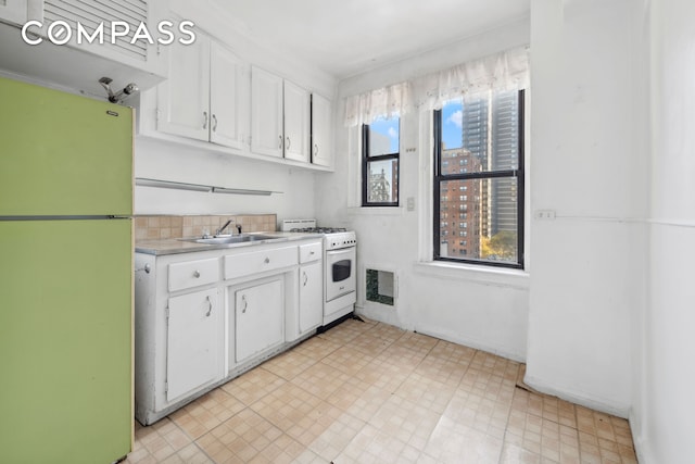 kitchen with white appliances, a sink, white cabinetry, and light countertops