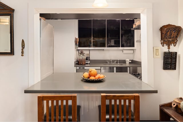 kitchen featuring stainless steel countertops, a sink, and dishwashing machine