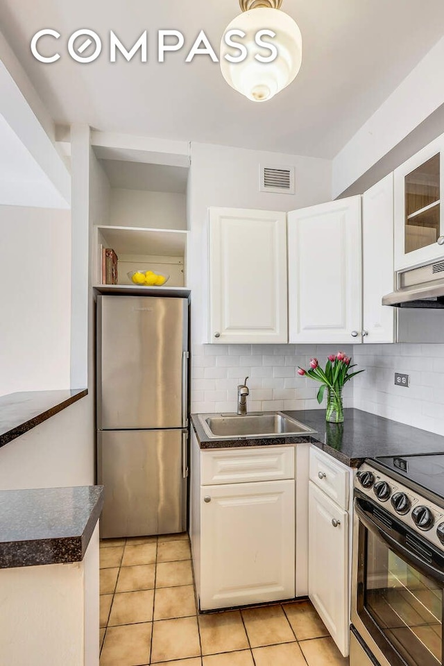 kitchen featuring freestanding refrigerator, under cabinet range hood, a sink, and white cabinetry