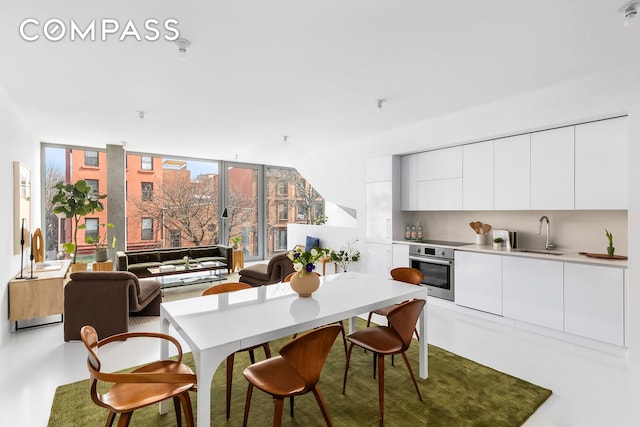 kitchen with stainless steel oven, modern cabinets, light countertops, white cabinetry, and a sink