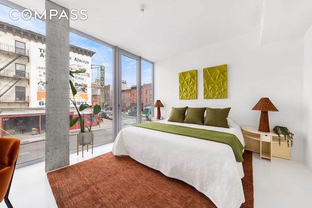 bedroom with a view of city, concrete flooring, expansive windows, and access to exterior