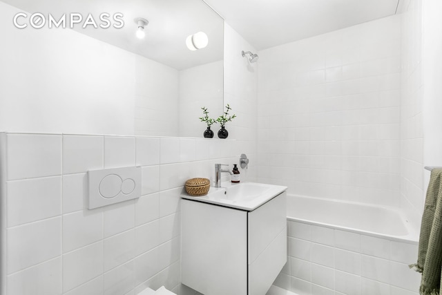 full bathroom featuring tile walls, vanity, and tiled shower / bath combo