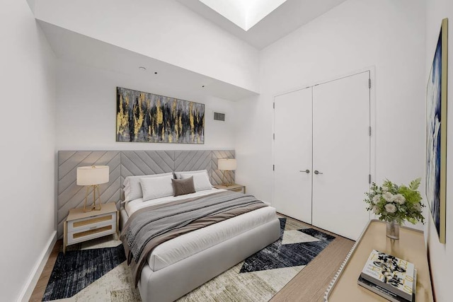 bedroom with baseboards, wood finished floors, a skylight, visible vents, and a closet