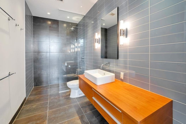 full bathroom with vanity, toilet, tile walls, a walk in shower, and tile patterned floors