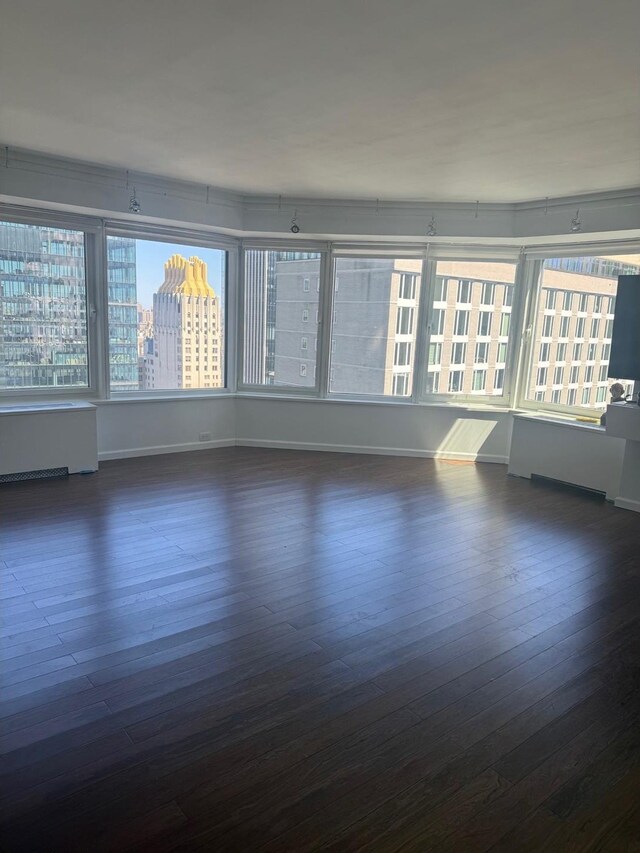 150 W 56th St Unit 3302, New York City, NY 10019 - unfurnished room with wood finished floors, baseboards, and radiator heating unit