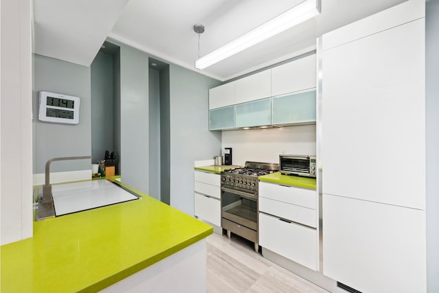 kitchen with white cabinetry, light countertops, stainless steel range with gas stovetop, a toaster, and hanging light fixtures