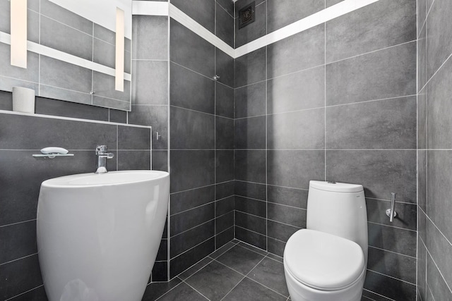 half bathroom with toilet and tile walls
