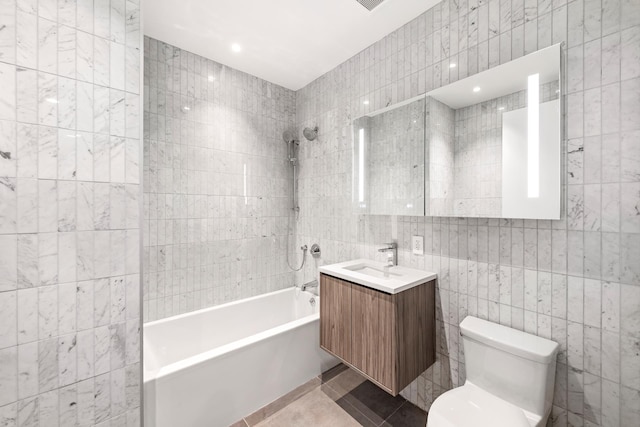 bathroom featuring tile walls, tile patterned flooring, washtub / shower combination, toilet, and vanity