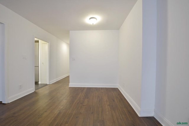 unfurnished room featuring baseboards and dark wood-style floors