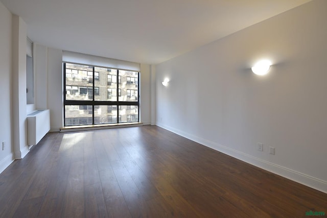 unfurnished room with baseboards, dark wood finished floors, and radiator