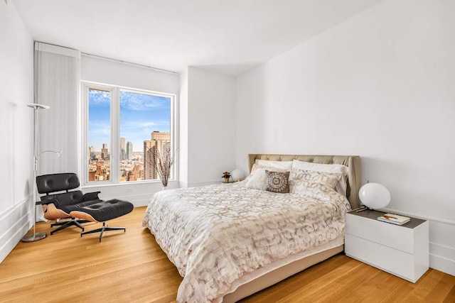 bedroom with a view of city and light wood-style flooring