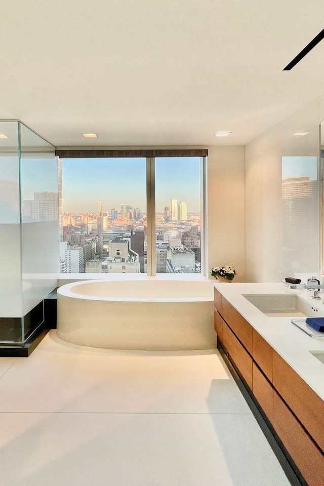 bathroom featuring a soaking tub, double vanity, a sink, tile patterned floors, and a view of city