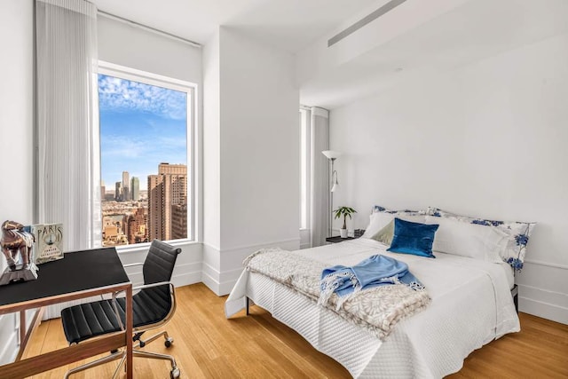 bedroom with a view of city, baseboards, and wood finished floors