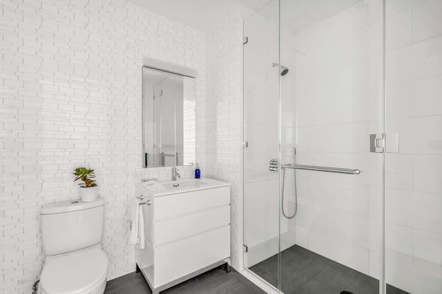 bathroom with vanity, a shower stall, toilet, and tile walls