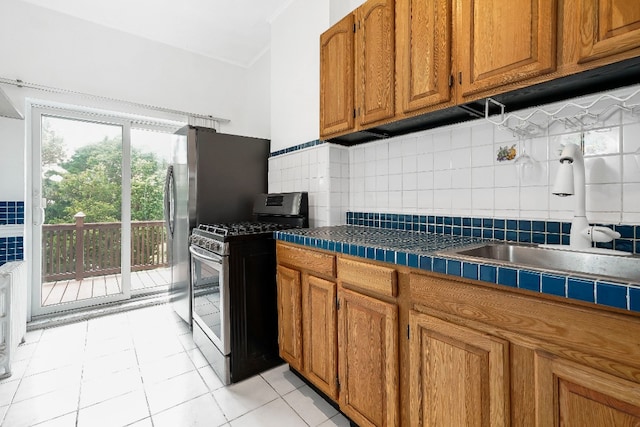 64-07 68th Ave, New York City, NY 11385 - kitchen featuring stainless steel gas stove, brown cabinetry, a sink, decorative backsplash, and light tile patterned floors