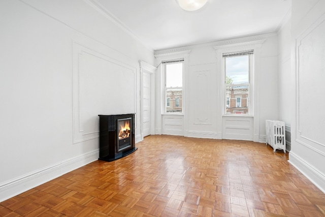 64-07 68th Ave, New York City, NY 11385 - unfurnished living room with radiator heating unit, crown molding, a lit fireplace, a decorative wall, and baseboards