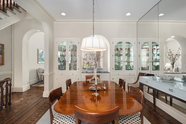 dining space with baseboards, arched walkways, ornamental molding, and recessed lighting