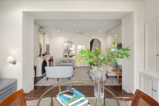 living room featuring wood finished floors, ornamental molding, baseboards, a fireplace, and ceiling fan