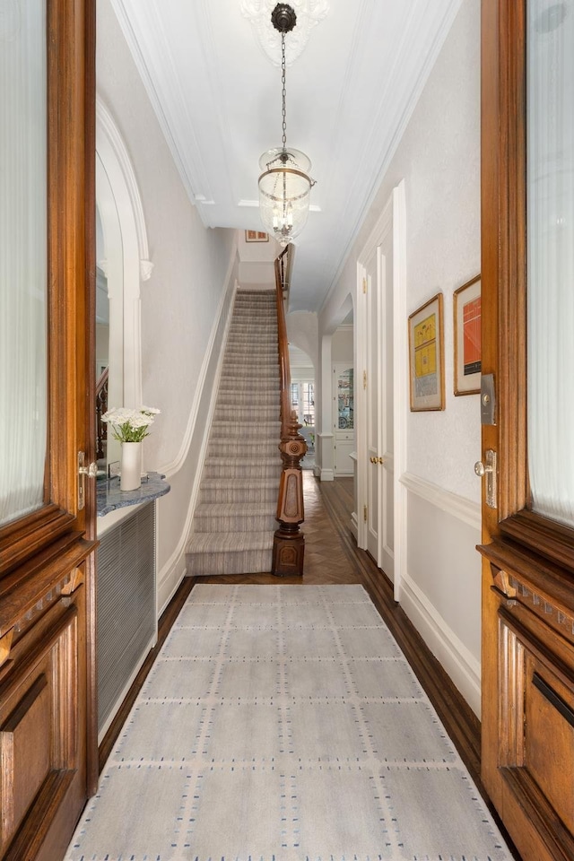 foyer entrance featuring stairway, wood finished floors, a notable chandelier, and ornamental molding