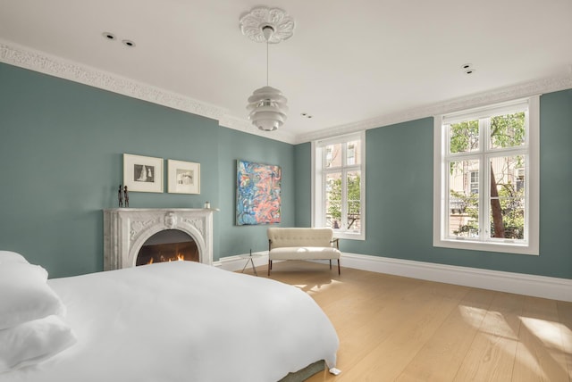 bedroom with baseboards, a lit fireplace, and wood finished floors