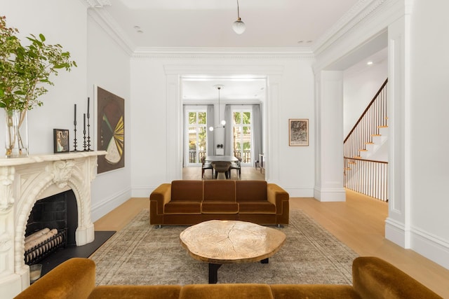 living room with a high end fireplace, wood finished floors, stairs, and ornamental molding
