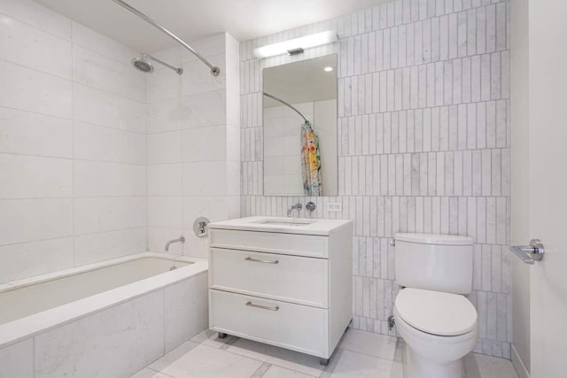 bathroom featuring vanity, tile patterned flooring, toilet, tiled shower / bath combo, and tile walls