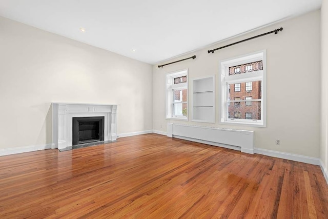 59 E 73rd St, New York City, NY 10021 - unfurnished living room featuring wood finished floors, radiator heating unit, baseboards, and a fireplace with flush hearth